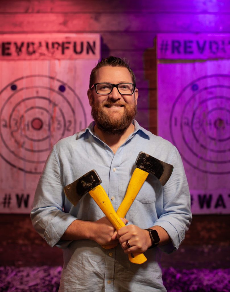 Man holding two axes at the axe throwing bar