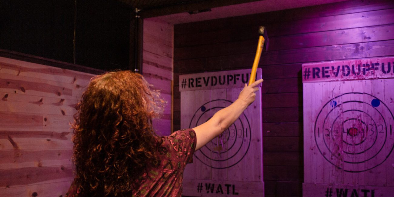 Woman throws axe at the target in the axe throwing bar